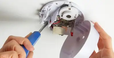 Certified technician wiring smoke detector during installation in Tampa, FL